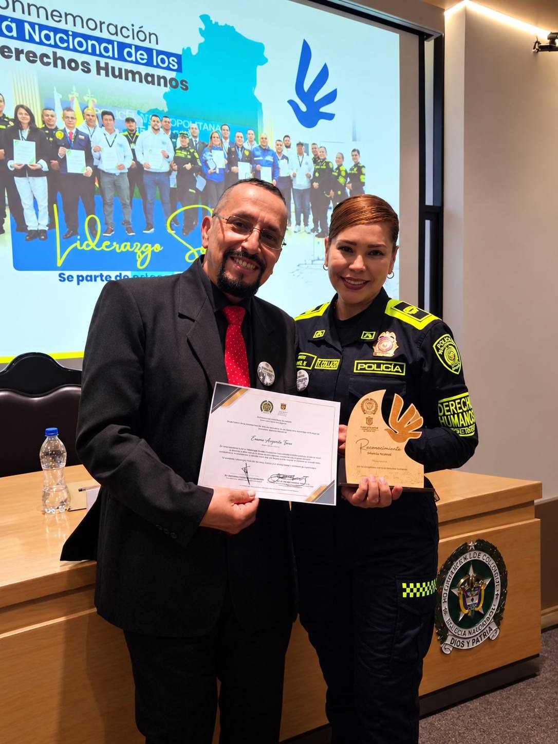 Erasmo Angarita Tovar recibe el diploma y la placa junto a una oficial de la Policía Metropolitana de Bogotá